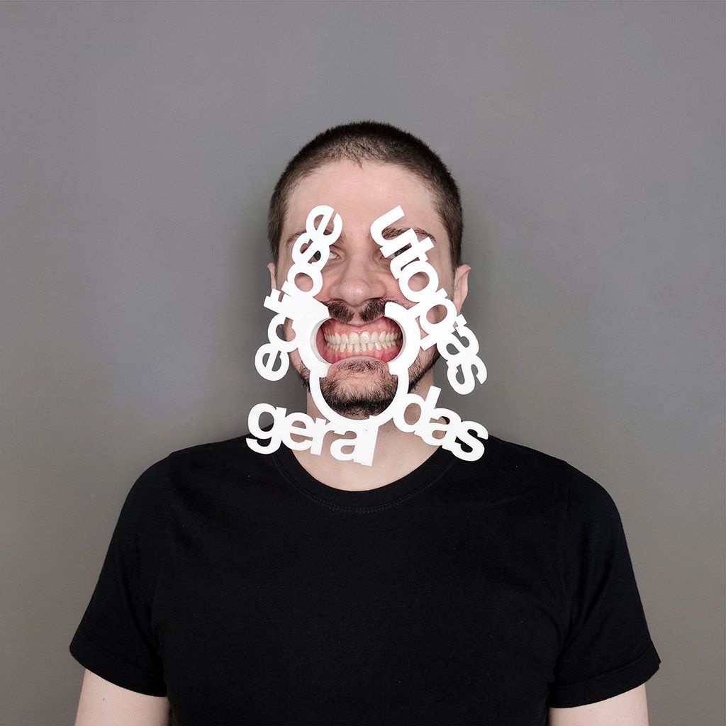 Um objeto é inserido entre os lábios da pessoa, mantendo seus dentes a mostra como um sorriso forçado, no entorno do objeto como uma extensão do mesmo material podemos ler as seguintes palavras: “Elipse geral das utopias”